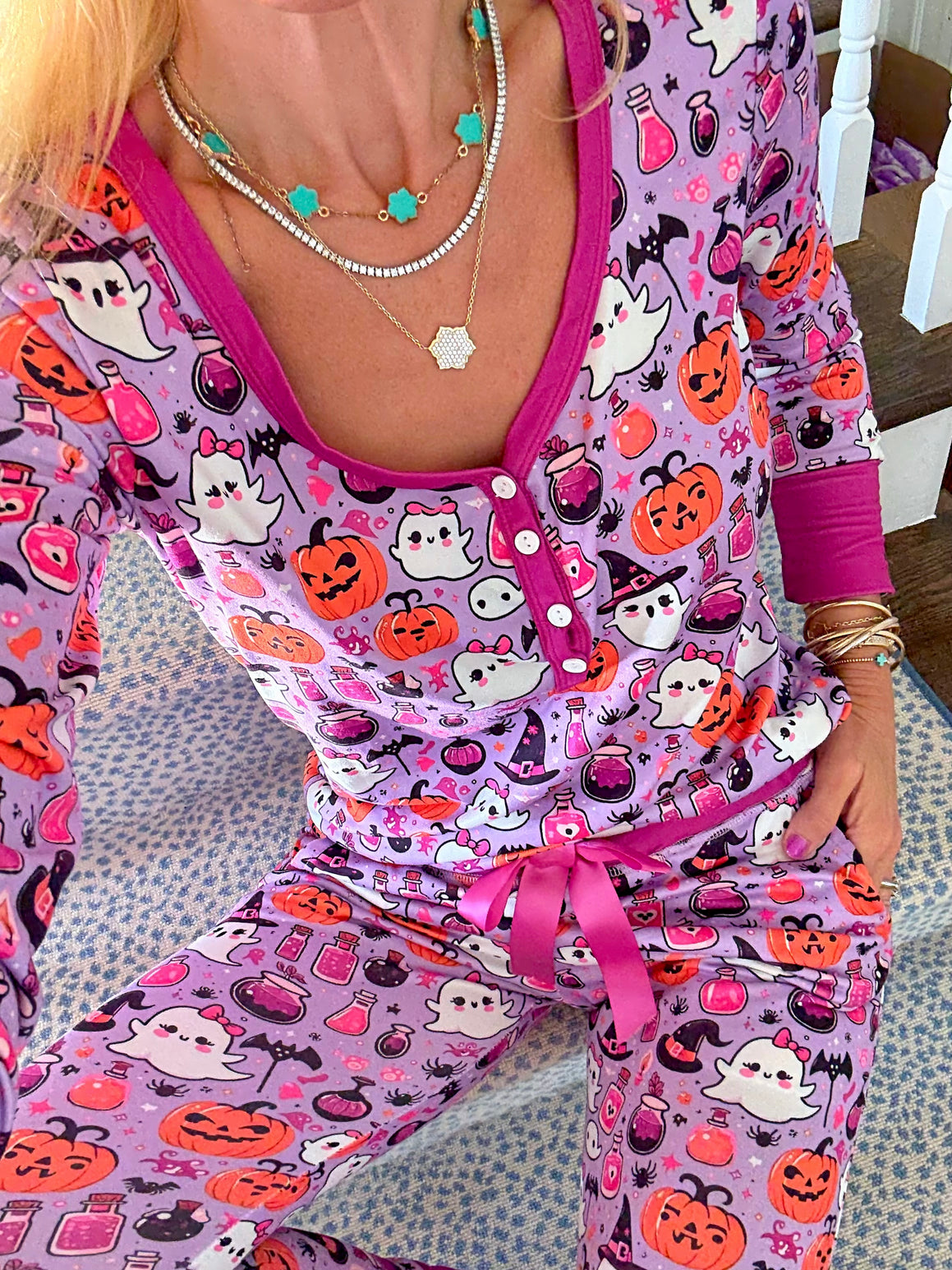 Person wearing a Halloween-themed outfit with pumpkins, ghosts, and cats on a pink background.