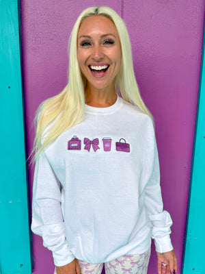 Woman wearing a white sweatshirt with colorful icons against a purple and teal background