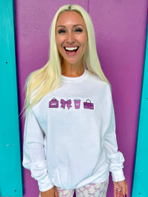 Woman wearing a white sweatshirt with colorful icons against a purple and teal background