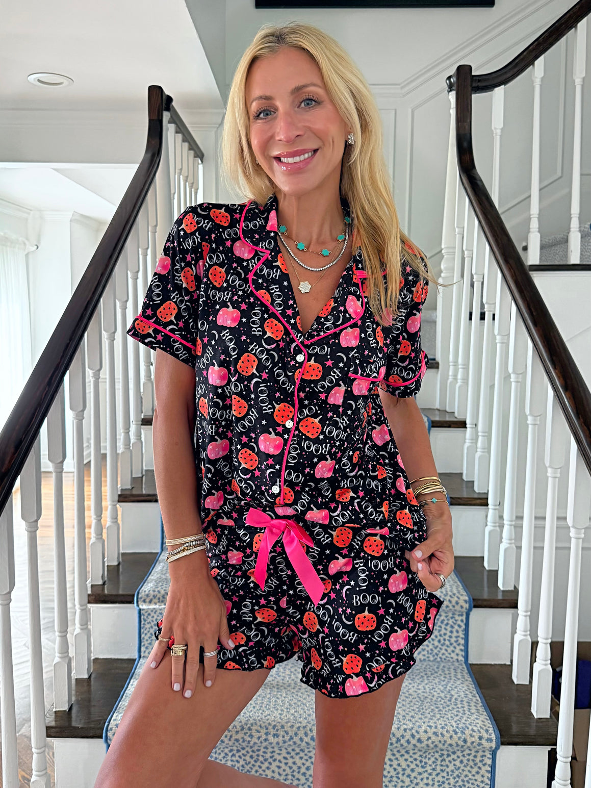 Woman wearing a black halloween pajama set with pink accents in a home setting.