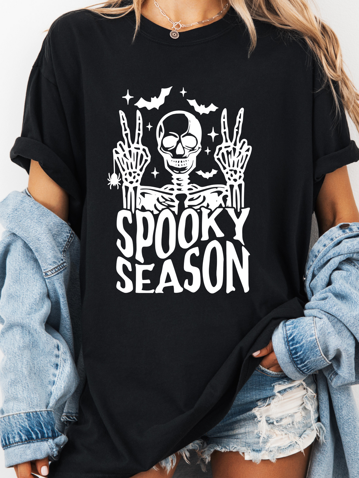 Black t-shirt with skeleton design and 'Spooky Season' text worn by a person.